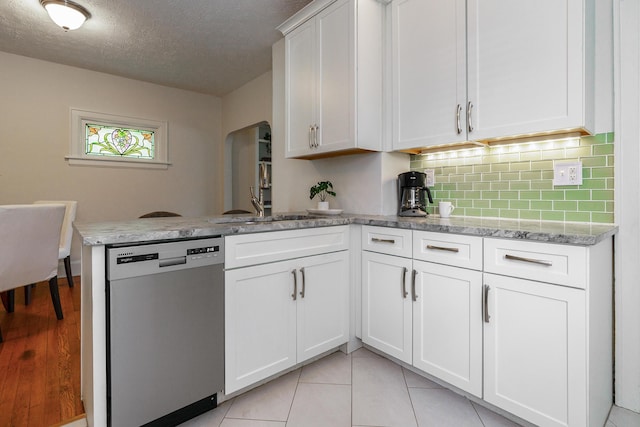338 Sheldon Ave, Columbus, OH 43207 - kitchen featuring stainless steel dishwasher, a peninsula, white cabinets, tasteful backsplash, and light stone countertops