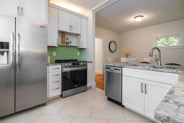 338 Sheldon Ave, Columbus, OH 43207 - kitchen featuring appliances with stainless steel finishes, decorative backsplash, open shelves, white cabinetry, and light stone counters