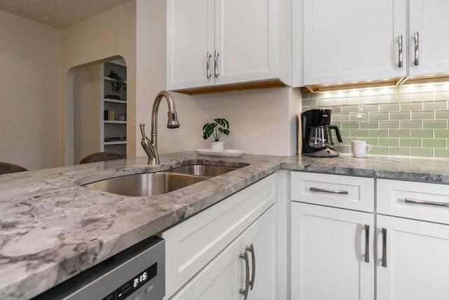 338 Sheldon Ave, Columbus, OH 43207 - kitchen featuring tasteful backsplash, stainless steel dishwasher, white cabinets, light stone countertops, and arched walkways