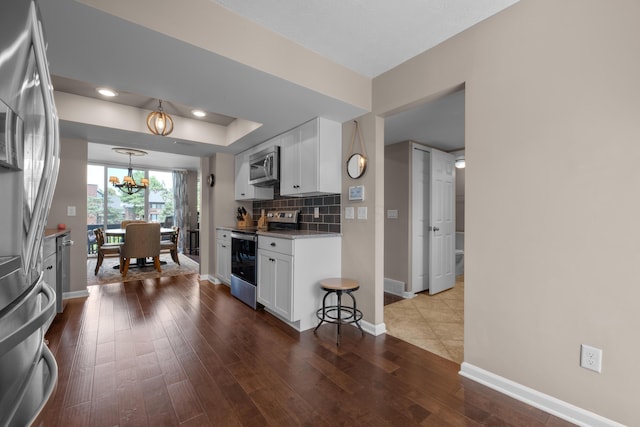 4758 Crazy Horse Ln Unit 2, Westerville, OH 43081 - kitchen with stainless steel appliances, a chandelier, white cabinetry, dark wood-style floors, and tasteful backsplash