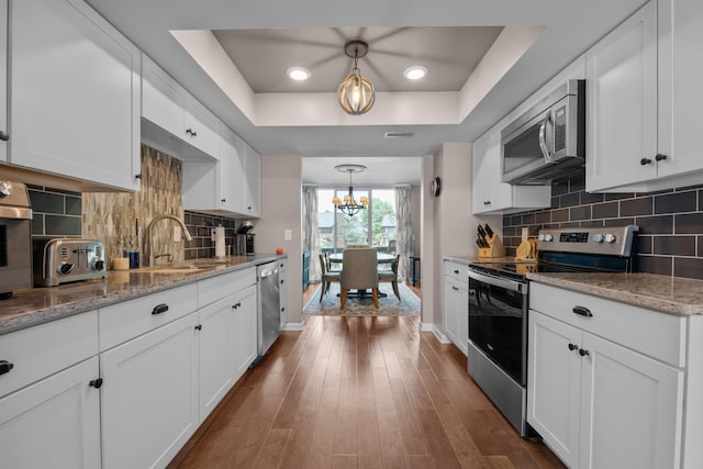 4758 Crazy Horse Ln Unit 2, Westerville, OH 43081 - kitchen featuring appliances with stainless steel finishes, a tray ceiling, a chandelier, and white cabinetry