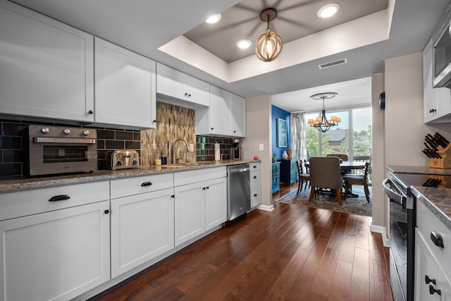 4758 Crazy Horse Ln Unit 2, Westerville, OH 43081 - kitchen with appliances with stainless steel finishes, a tray ceiling, a chandelier, decorative backsplash, and white cabinetry