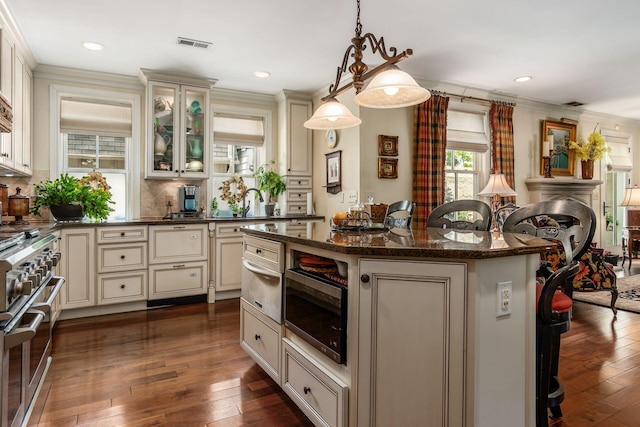 161 Jackson St, Columbus, OH 43206 - kitchen with cream cabinets, stainless steel appliances, a kitchen island, a warming drawer, and dark wood finished floors