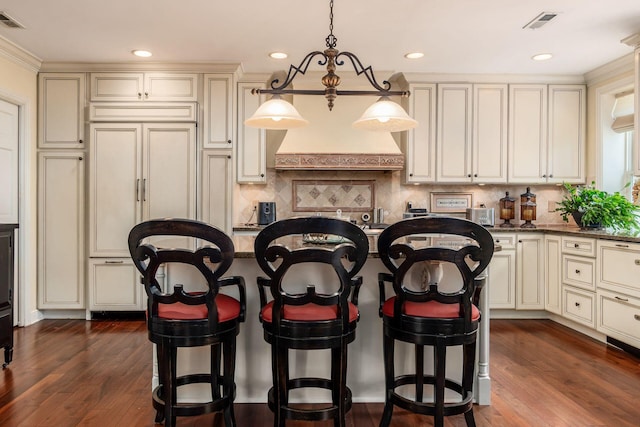 161 Jackson St, Columbus, OH 43206 - kitchen featuring cream cabinetry, paneled fridge, a breakfast bar area, decorative backsplash, and a kitchen island