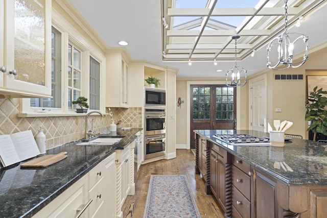 130 Boving Rd, Lancaster, OH 43130 - kitchen featuring a chandelier, light wood-style floors, glass insert cabinets, decorative backsplash, and a skylight