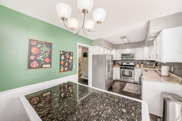 2328 Terrance Dr Unit 76, Columbus, OH 43220 - kitchen with stainless steel appliances, white cabinetry, a chandelier, light stone countertops, and wainscoting