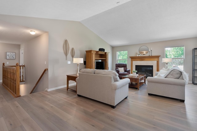8090 Tree Lake Blvd, Powell, OH 43065 - living area featuring a glass covered fireplace, light wood-type flooring, vaulted ceiling, and plenty of natural light