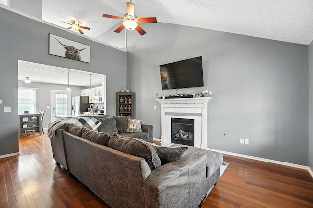 4764 Mattox St Unit 44, Columbus, OH 43228 - living room with dark wood-style flooring, a ceiling fan, a glass covered fireplace, high vaulted ceiling, and a textured ceiling