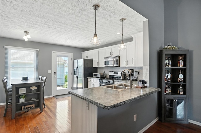 4764 Mattox St Unit 44, Columbus, OH 43228 - kitchen with appliances with stainless steel finishes, wood finished floors, tasteful backsplash, white cabinets, and a peninsula