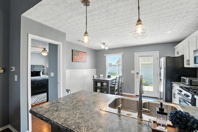 4764 Mattox St Unit 44, Columbus, OH 43228 - kitchen featuring white cabinets, appliances with stainless steel finishes, hanging light fixtures, wood finished floors, and dark countertops