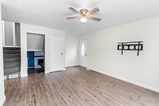 2483 Onyx Ct, Grove City, OH 43123 - unfurnished living room with stairway, a ceiling fan, wood finished floors, a fireplace, and a textured ceiling