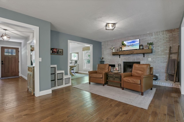 10 Denbigh Dr, Granville, OH 43023 - living room with dark wood finished floors, a brick fireplace, healthy amount of natural light, and a textured ceiling