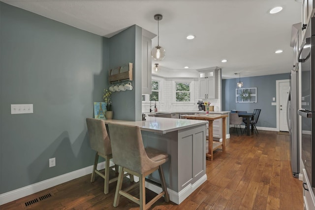 10 Denbigh Dr, Granville, OH 43023 - kitchen featuring a peninsula, dark wood-type flooring, recessed lighting, decorative light fixtures, and light countertops