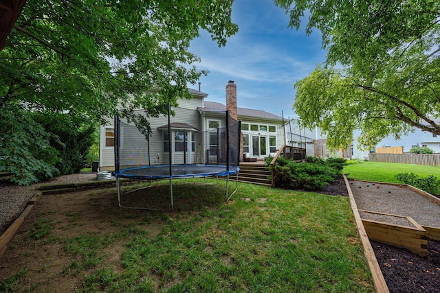 4247 Boulder Creek Dr, Columbus, OH 43230 - rear view of property featuring a trampoline, a wooden deck, a chimney, and a garden