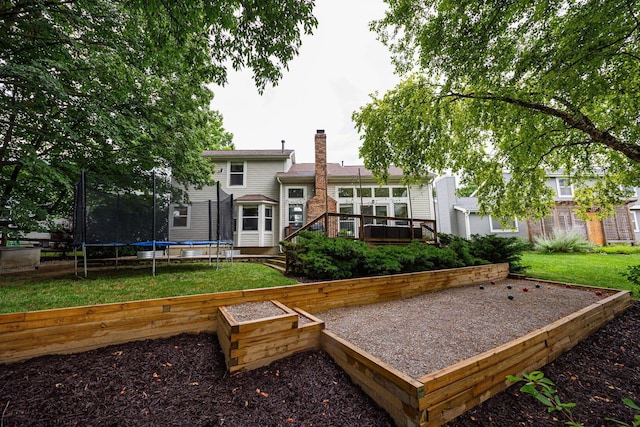 4247 Boulder Creek Dr, Columbus, OH 43230 - back of house with a trampoline, a wooden deck, a chimney, and a yard