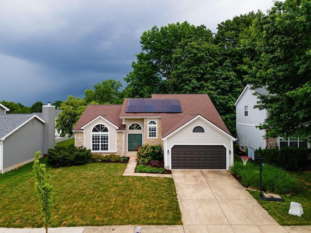 4247 Boulder Creek Dr, Columbus, OH 43230 - view of front of house with roof mounted solar panels, a front yard, concrete driveway, an attached garage, and stone siding