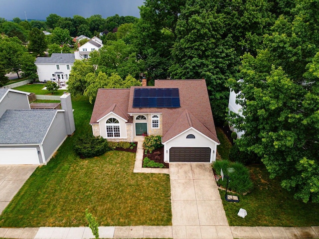 4247 Boulder Creek Dr, Columbus, OH 43230 - view of front of house with concrete driveway, roof mounted solar panels, a front lawn, a chimney, and an attached garage