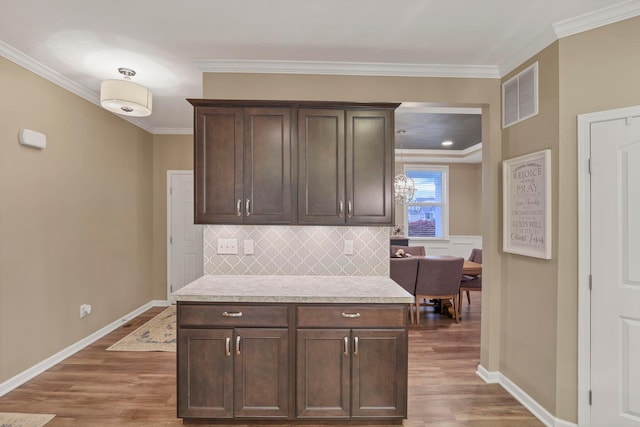 2267 Holiday Valley Dr, Grove City, OH 43123 - kitchen with wood finished floors, dark brown cabinets, light countertops, decorative backsplash, and crown molding