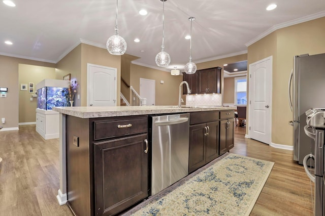 2267 Holiday Valley Dr, Grove City, OH 43123 - kitchen with stainless steel appliances, light countertops, dark brown cabinetry, light wood-style flooring, and a center island with sink