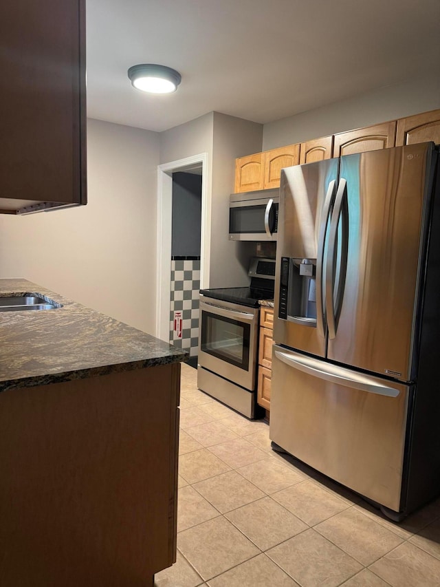 5542 Emerson Ave, Worthington, OH 43085 - kitchen with appliances with stainless steel finishes, light brown cabinetry, light tile patterned floors, and dark stone counters