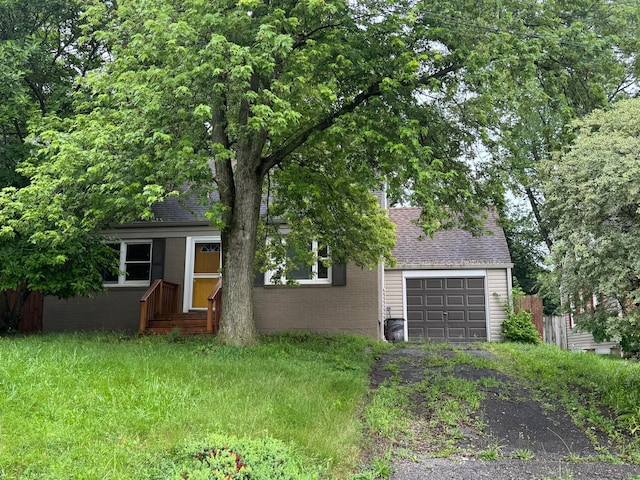 5542 Emerson Ave, Worthington, OH 43085 - view of property hidden behind natural elements featuring driveway, a garage, roof with shingles, and brick siding