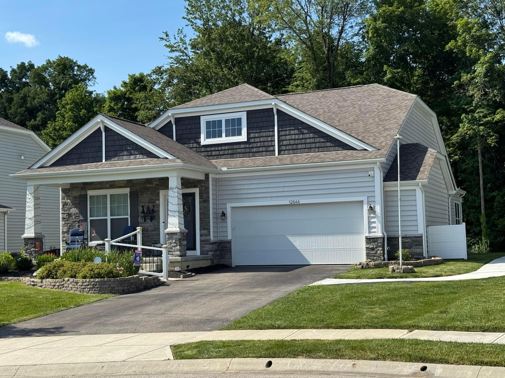 12644 Prairie View Dr NW, Pickerington, OH 43147 - craftsman-style home featuring stone siding, driveway, an attached garage, a front yard, and a porch
