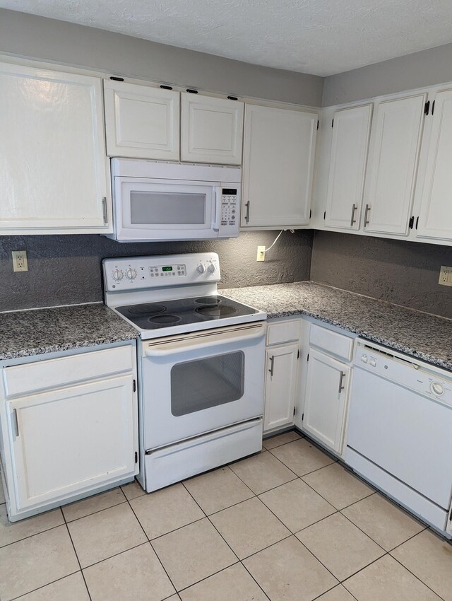 6679 Brock St, Dublin, OH 43017 - kitchen with white appliances, white cabinetry, light tile patterned floors, a textured ceiling, and dark stone counters