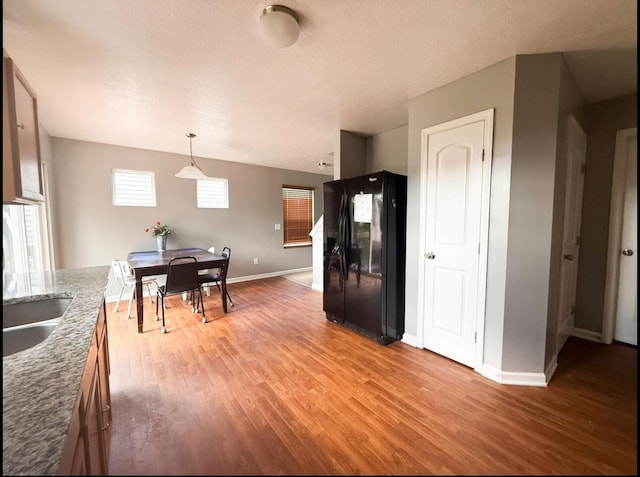 7173 Serenoa Dr, Reynoldsburg, OH 43068 - kitchen with black fridge with ice dispenser, light wood-style flooring, stone counters, and pendant lighting