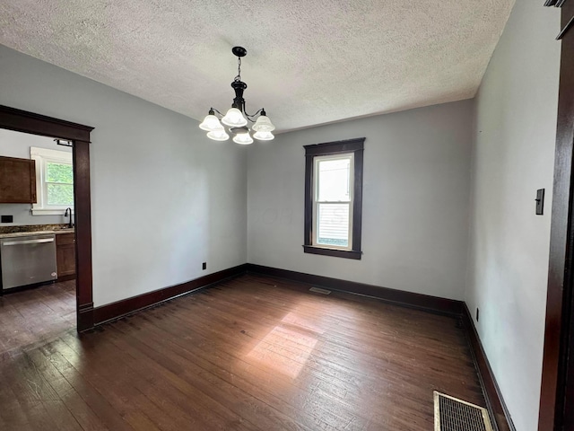 940 W 3rd St, Logan, OH 43138 - empty room featuring a chandelier, dark wood-type flooring, plenty of natural light, and a textured ceiling