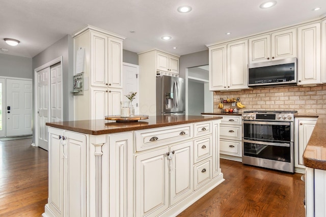 2063 Hayer Ct, Lewis Center, OH 43035 - kitchen featuring stainless steel appliances, dark countertops, dark wood-style floors, decorative backsplash, and a center island