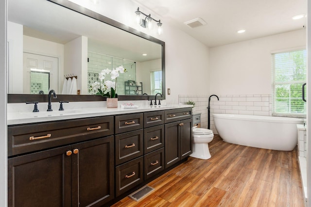 2063 Hayer Ct, Lewis Center, OH 43035 - full bath with double vanity, tile walls, a freestanding tub, wood finished floors, and a shower with shower door