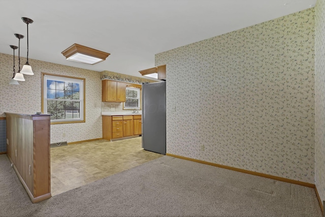 19 Kirby Rd, Heath, OH 43056 - kitchen with wallpapered walls, freestanding refrigerator, hanging light fixtures, light countertops, and brown cabinets