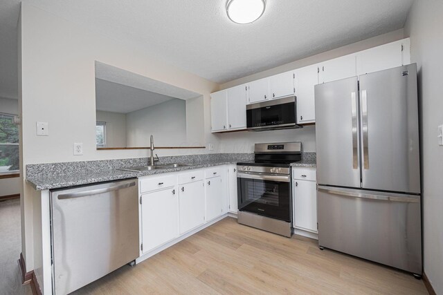 7599 Worth Galena Rd Unit 38, Worthington, OH 43085 - kitchen featuring appliances with stainless steel finishes, light wood-style floors, white cabinets, and light stone countertops