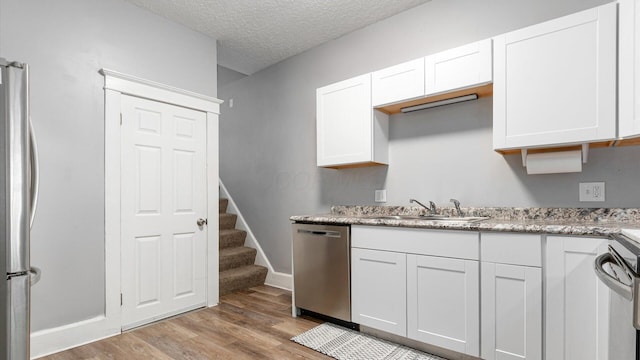 467 Mount Vernon Rd, Newark, OH 43055 - kitchen featuring appliances with stainless steel finishes, light wood-style floors, white cabinets, and a textured ceiling
