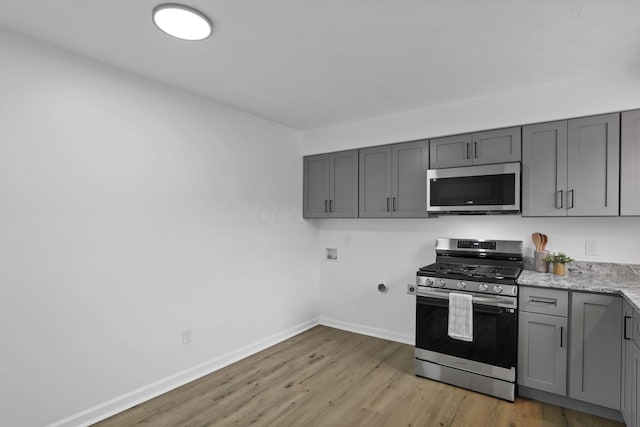 5781 Hallridge Cir Unit B, Columbus, OH 43232 - kitchen featuring appliances with stainless steel finishes, gray cabinetry, light wood-type flooring, and light stone counters