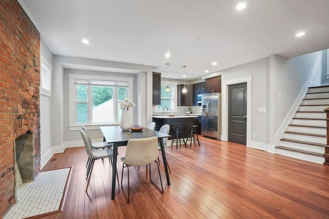 1867 Bryden Rd, Columbus, OH 43205 - dining area with stairs, a brick fireplace, light wood finished floors, recessed lighting, and brick wall