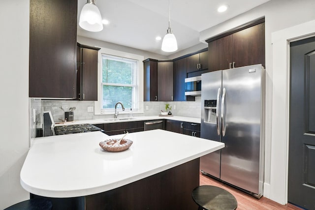 1867 Bryden Rd, Columbus, OH 43205 - kitchen with stainless steel appliances, dark brown cabinetry, light countertops, a peninsula, and tasteful backsplash