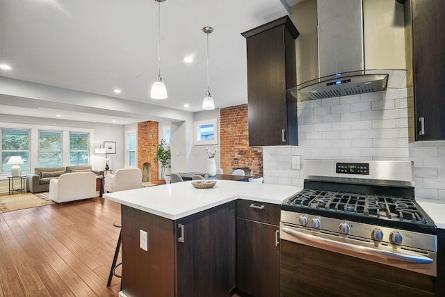 1867 Bryden Rd, Columbus, OH 43205 - kitchen with stainless steel gas range oven, wall chimney range hood, open floor plan, light countertops, and dark brown cabinets
