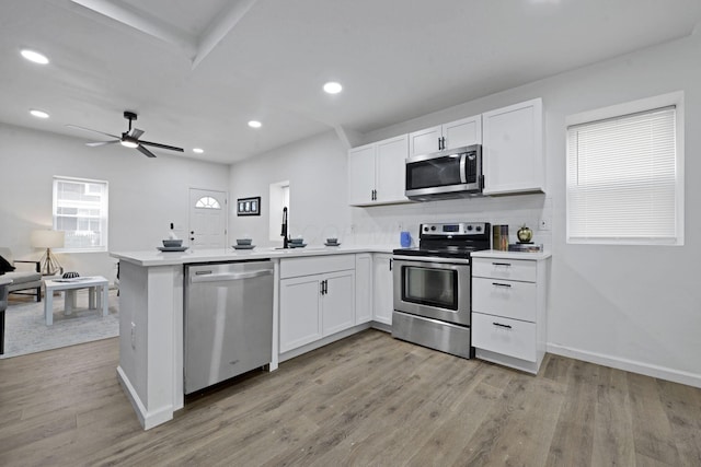 863 Carpenter St, Columbus, OH 43206 - kitchen with appliances with stainless steel finishes, a peninsula, white cabinetry, light wood-style floors, and light countertops