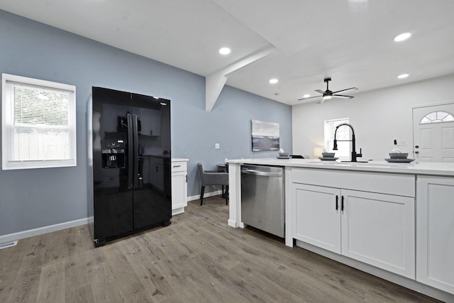 863 Carpenter St, Columbus, OH 43206 - kitchen with black fridge, stainless steel dishwasher, ceiling fan, light wood finished floors, and white cabinets