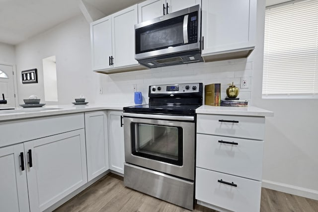 863 Carpenter St, Columbus, OH 43206 - kitchen featuring appliances with stainless steel finishes, light wood-style floors, light countertops, decorative backsplash, and white cabinetry
