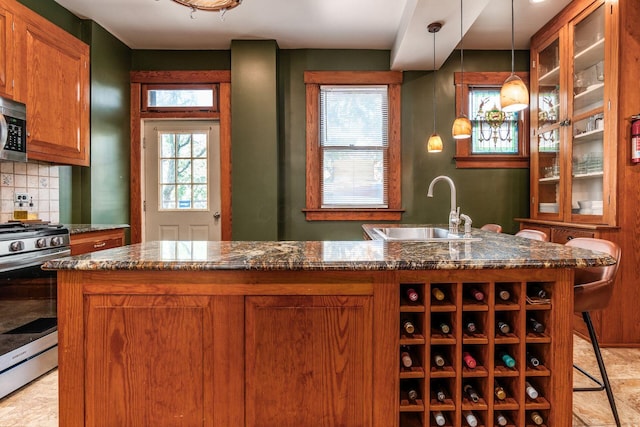 1412 Bryden Rd, Columbus, OH 43205 - kitchen with appliances with stainless steel finishes, brown cabinetry, backsplash, and decorative light fixtures