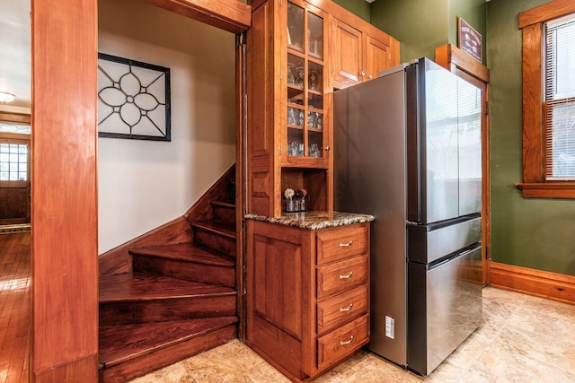 1412 Bryden Rd, Columbus, OH 43205 - kitchen featuring freestanding refrigerator, brown cabinets, glass insert cabinets, and dark stone countertops