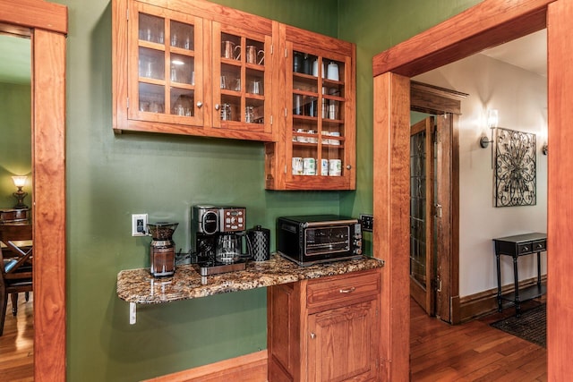 1412 Bryden Rd, Columbus, OH 43205 - kitchen with wood finished floors, glass insert cabinets, dark stone countertops, and brown cabinetry