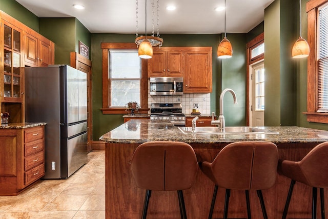 1412 Bryden Rd, Columbus, OH 43205 - kitchen featuring stainless steel appliances, brown cabinetry, decorative backsplash, a kitchen bar, and recessed lighting
