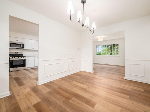 6019 Beechcroft Rd, Columbus, OH 43229 - unfurnished dining area with light wood-style floors, a chandelier, a wainscoted wall, and a decorative wall