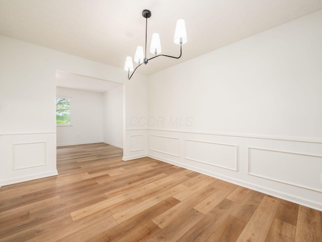 6019 Beechcroft Rd, Columbus, OH 43229 - unfurnished room with a chandelier, light wood-style floors, a decorative wall, and wainscoting