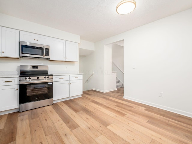 6019 Beechcroft Rd, Columbus, OH 43229 - kitchen with stainless steel appliances, light countertops, light wood-style flooring, white cabinets, and a textured ceiling