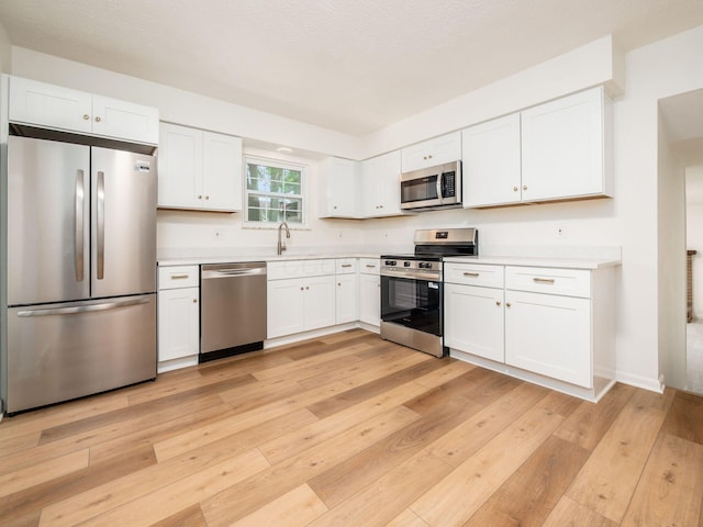 6019 Beechcroft Rd, Columbus, OH 43229 - kitchen featuring appliances with stainless steel finishes, light countertops, light wood-style floors, and white cabinetry