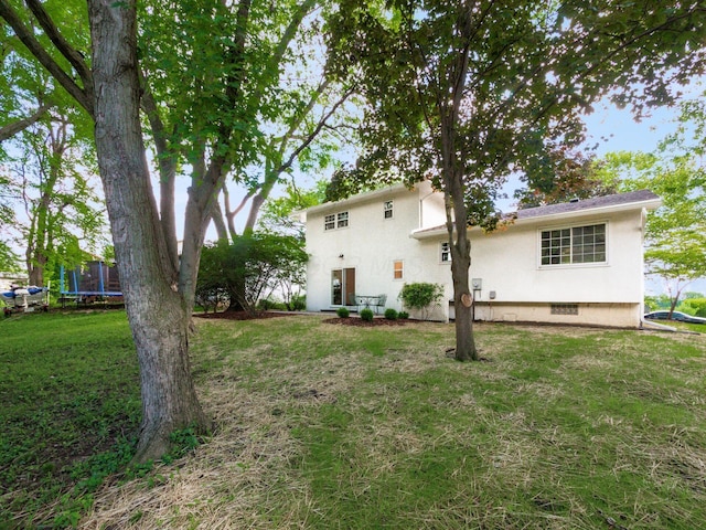6019 Beechcroft Rd, Columbus, OH 43229 - rear view of house featuring a trampoline, a lawn, and stucco siding